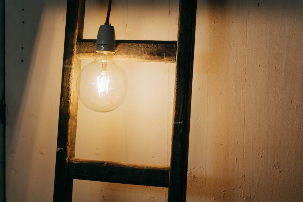 Close up image of a real ladder and a light bulb. Visual representation of the inspiration basic ladder logic programming can allow for.