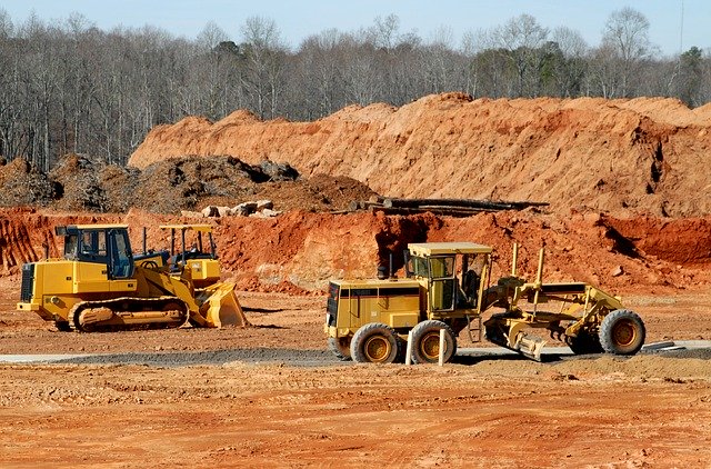 Heavy equipment moves dirt at a construction site. 