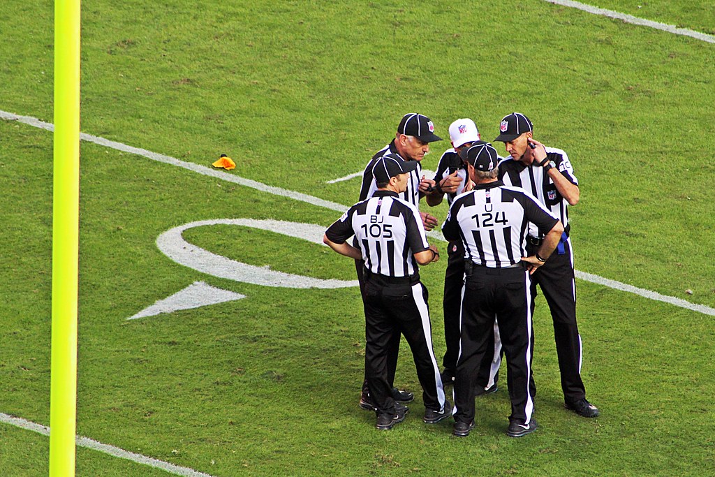 Officials on an NFL field.  Augmented Reality is used to help viewers watching the NFL. 