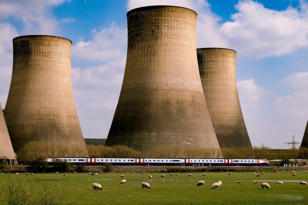 Photo for article on gas turbine controls.  Sheep graze in front of a locomotive as it passes in front of a power station. 
