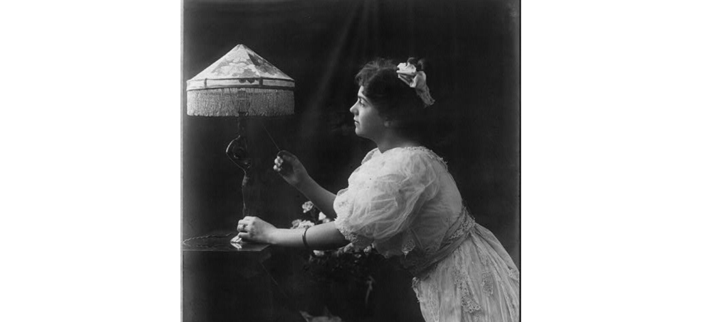 A 1908 General Electric advertising photo shows a woman with an electric lamp.  From Library of Congress.